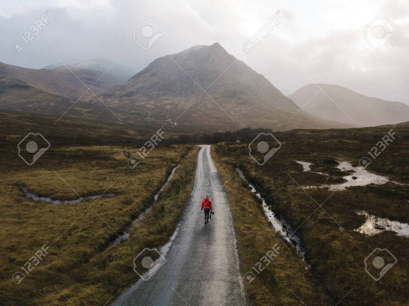Woman walking on a road in Glen Etive, Scotland - 122425581 Woman walking on a road in Glen Etive, Scotland - 122425581