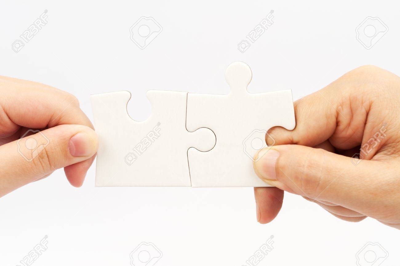two hands holding puzzle pieces and connecting them stock photo