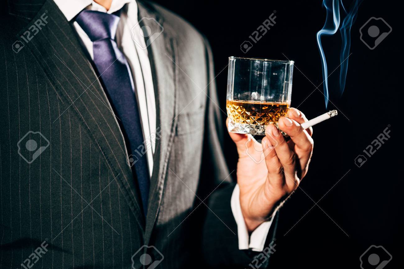 ウィスキーとタバコのガラスを保持しているスーツの男 の写真素材 画像素材 Image