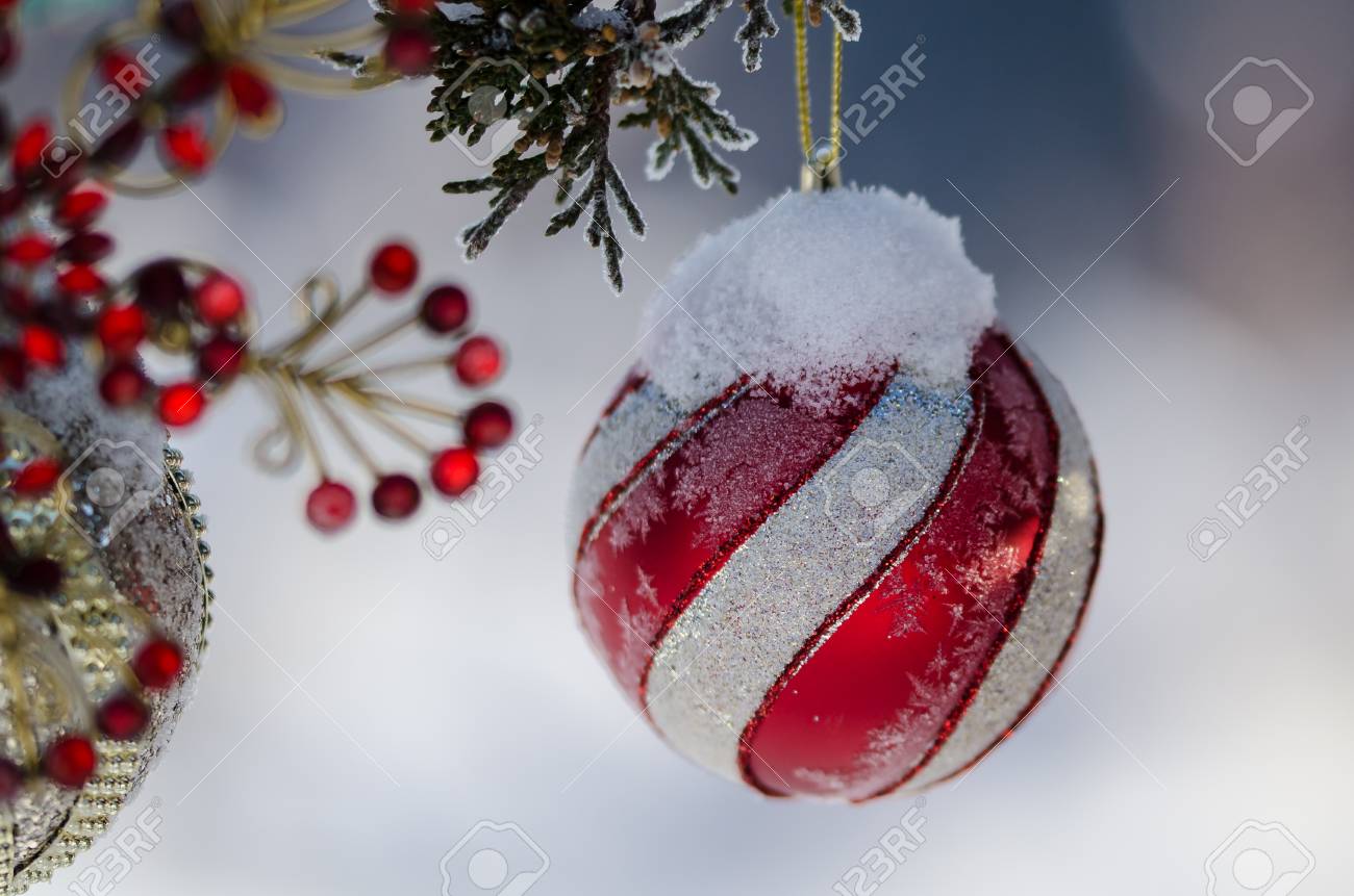 frozen red striped christmas ornament decorating a snowy outdoor frozen christmas decorations