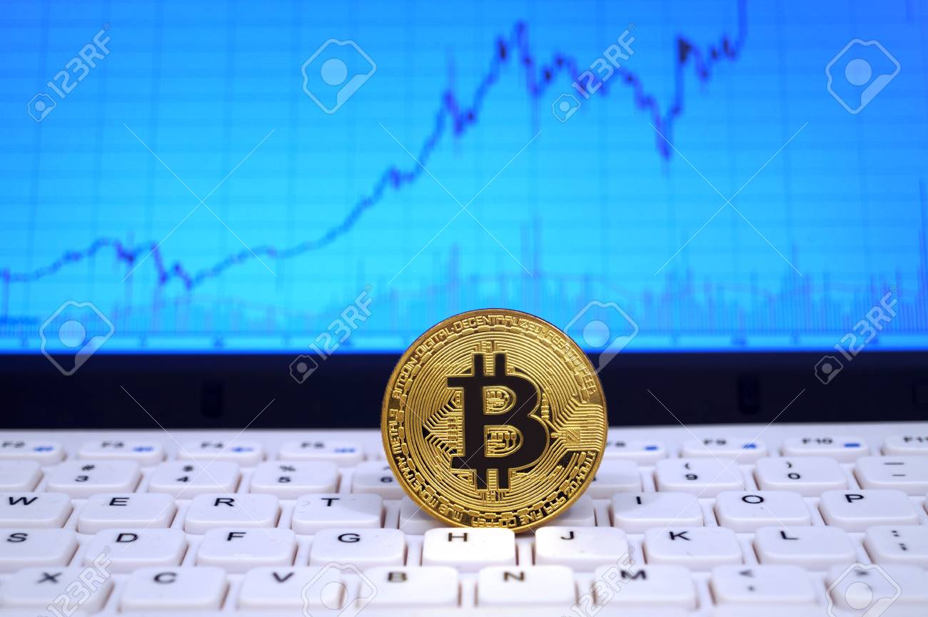 Coin Of Bitcoin On White Keyboard With Exchange Rate Graph On - 