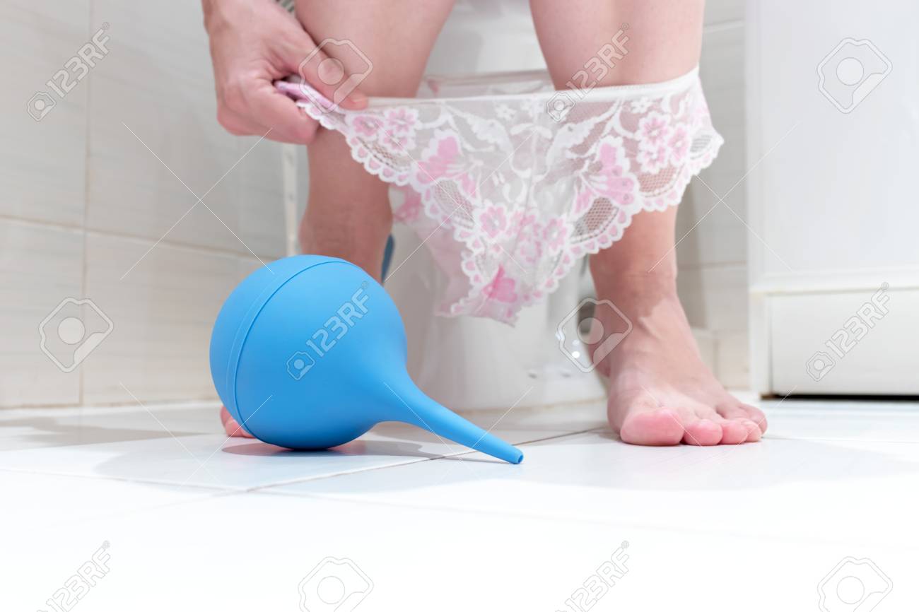 女性の浣腸　画像 低いパンティーと青いクレンジング浣腸を前にしたトイレに座っている女性のトリミングされた足。消化器系の問題とトイレの難しさのコンセプトイメージ。の写真素材・画像素材  Image 113274037