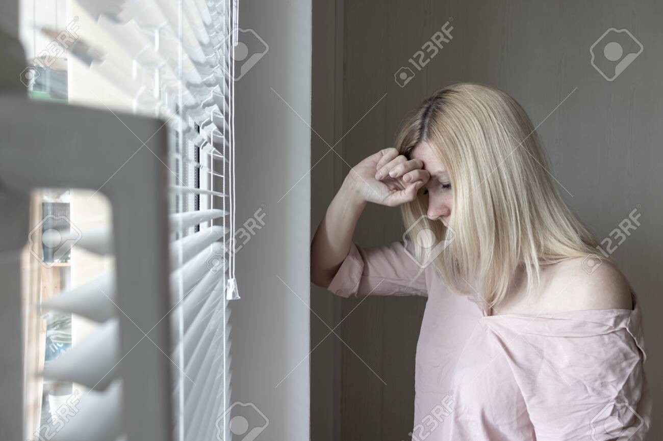 Sad apathetic lonely woman looking through a window at home or hotel, divorce, depression and apathy concept. - 121137882 Sad apathetic lonely woman looking through a window at home or hotel, divorce, depression and apathy concept. - 121137882