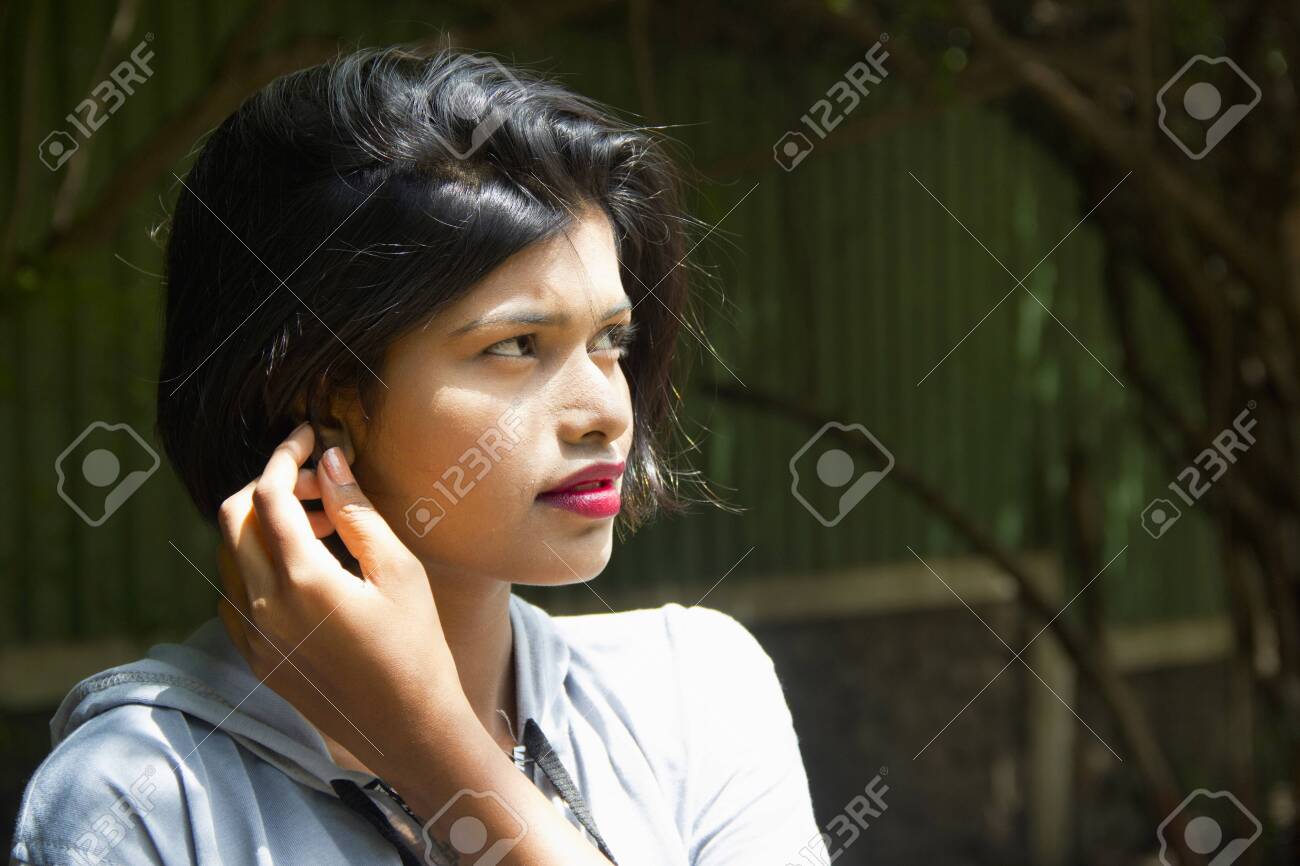 Young Indian Girl With Short Hair With Her Hand Near Ear Looking