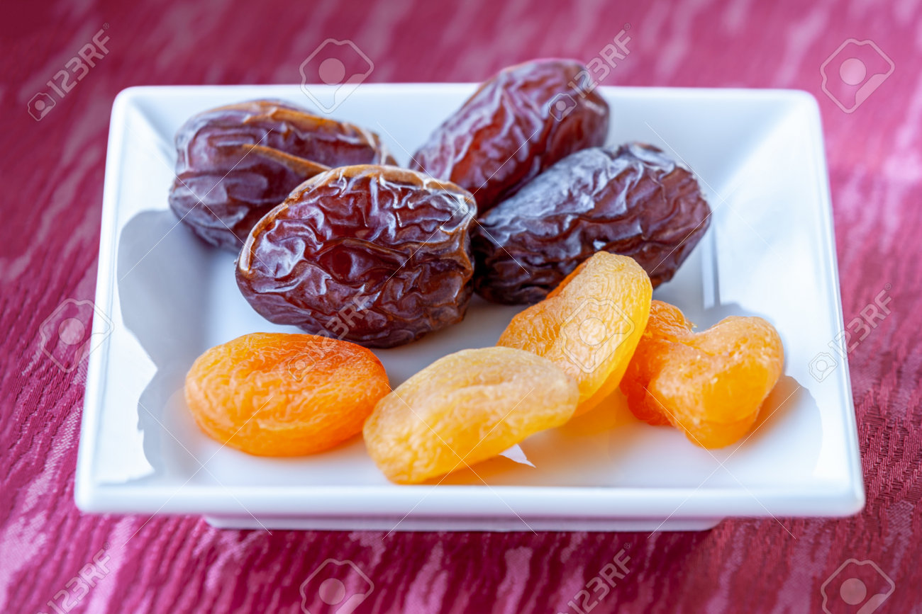 Plenty of dates and apricot arranged in a white bowl - 162919057 Plenty of dates and apricot arranged in a white bowl - 162919057