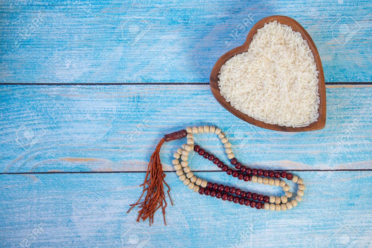 ZAKAT donation for Muslim according to religious principles during the Ramadan month, concept: rice grain in bow and rosary on wood - 148383500 ZAKAT donation for Muslim according to religious principles during the Ramadan month, concept: rice grain in bow and rosary on wood - 148383500