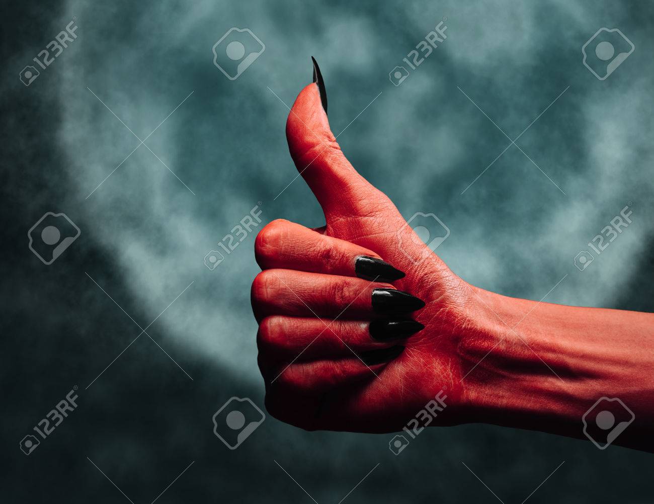 red demon or devil hand with thumb up gesture on full moon
