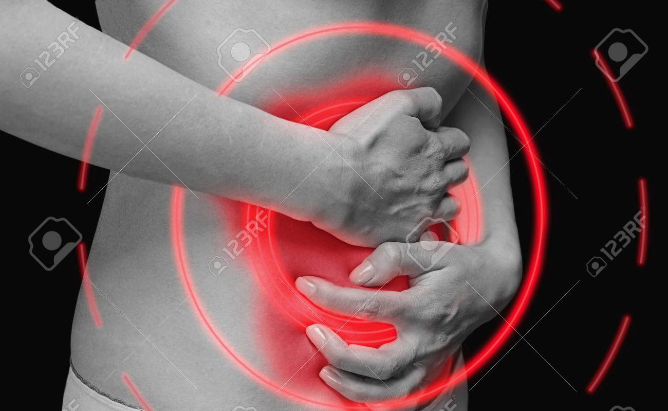 Unrecognizable woman holds her abdomen, side view, abdominal or menstrual pain, monochrome image, painful area of red color. - 37293921 Unrecognizable woman holds her abdomen, side view, abdominal or menstrual pain, monochrome image, painful area of red color. - 37293921