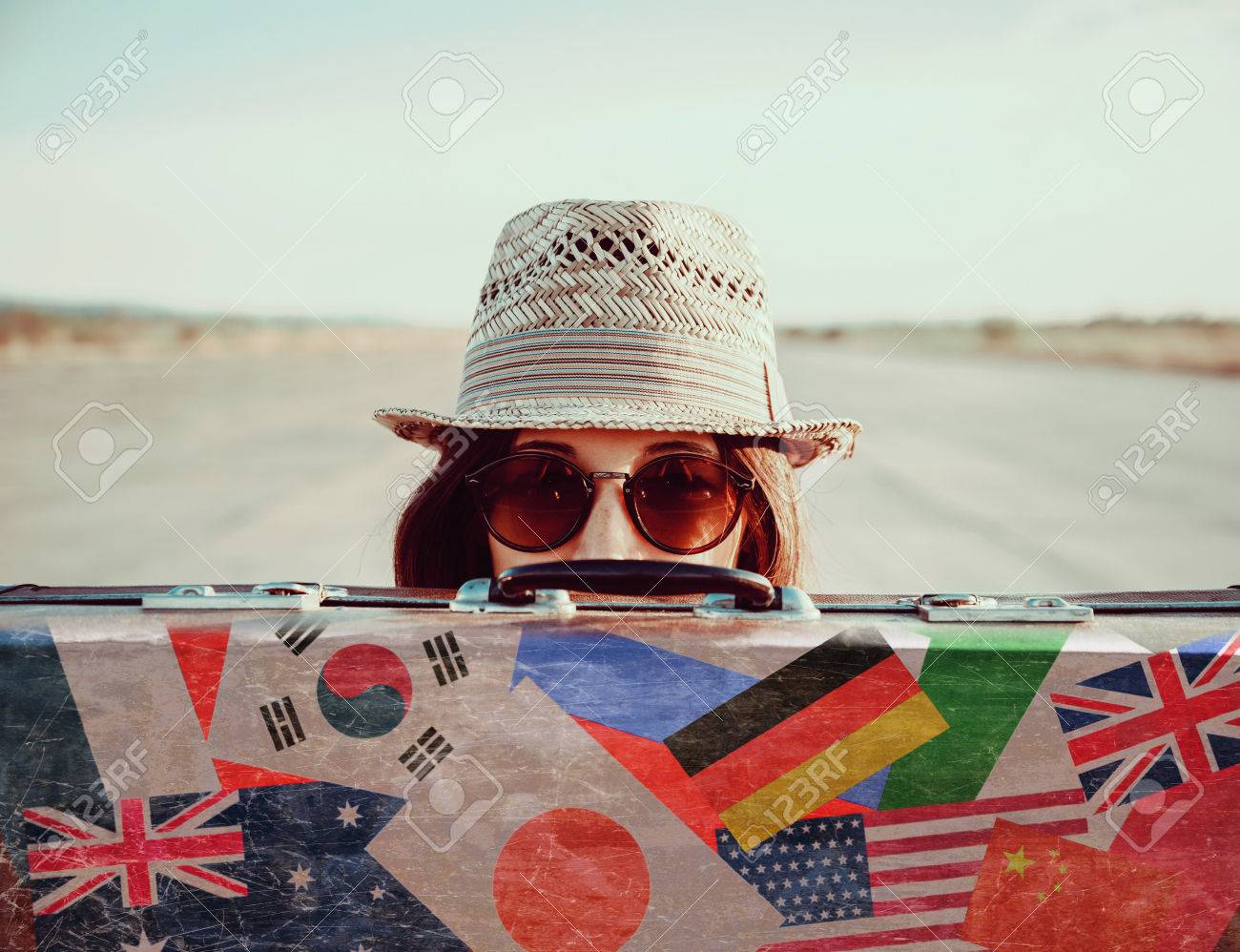 Hipster girl in a hat and sunglasses looks out from vintage suitcase. Suitcase with stamps flags of different country - 38610009 Hipster girl in a hat and sunglasses looks out from vintage suitcase. Suitcase with stamps flags of different country - 38610009