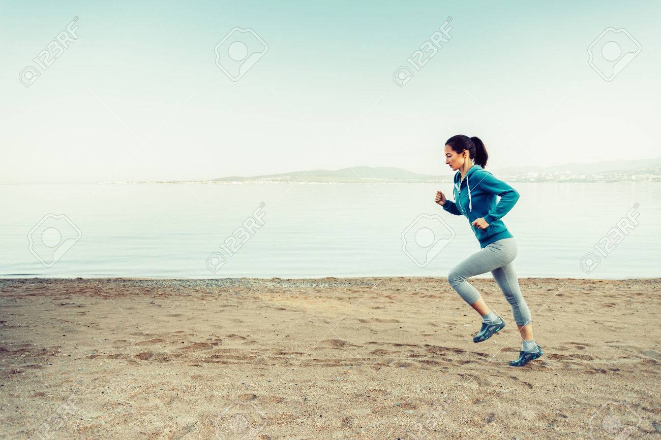 girl running on sand beach near the sea in summer in the morning