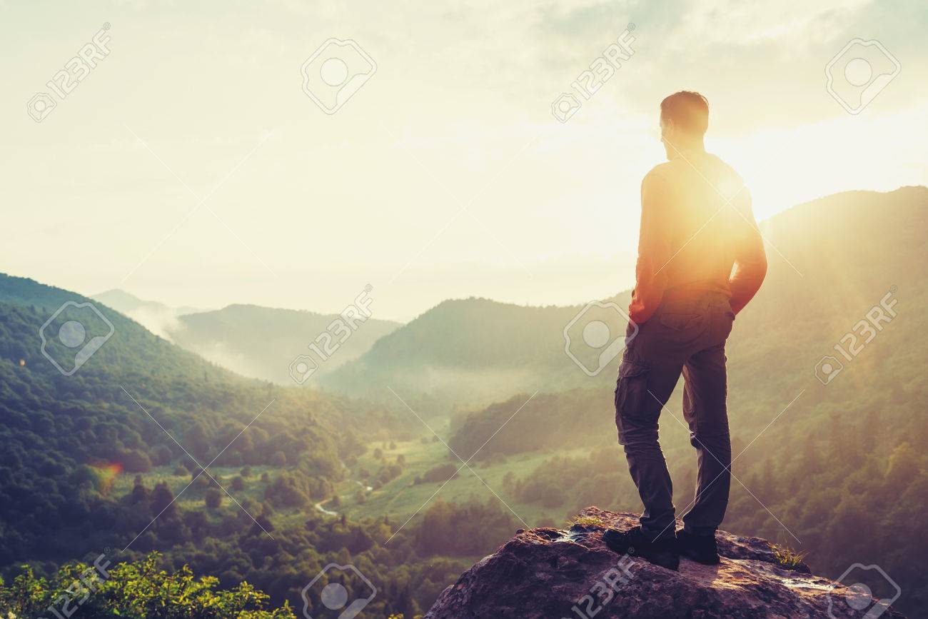 Traveler young man standing in the summer mountains at sunset and enjoying view of nature. Image with color - 62427681 Traveler young man standing in the summer mountains at sunset and enjoying view of nature. Image with color - 62427681