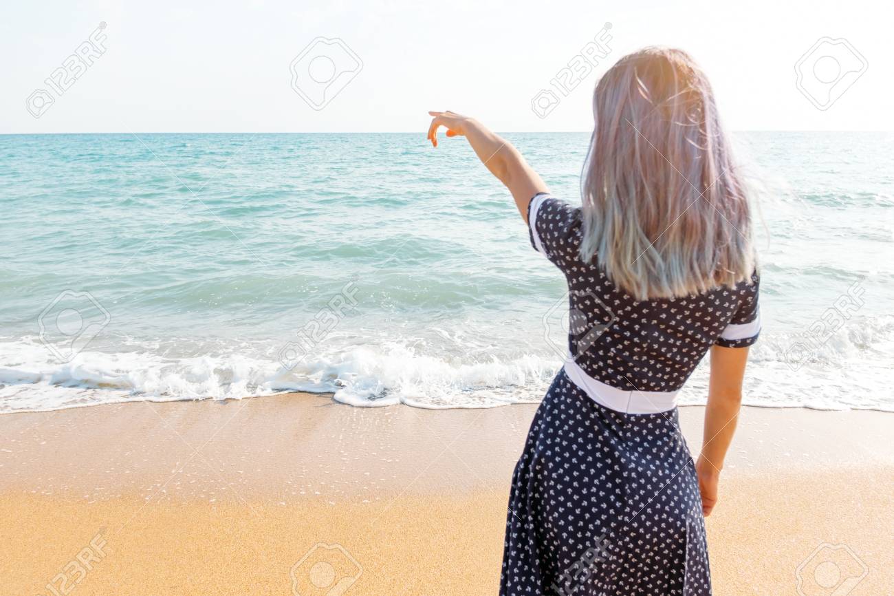 Young Woman In Dress Standing On Sand Beach And Pointing At Sea Rear View Stock Photo Picture And Royalty Free Image Image