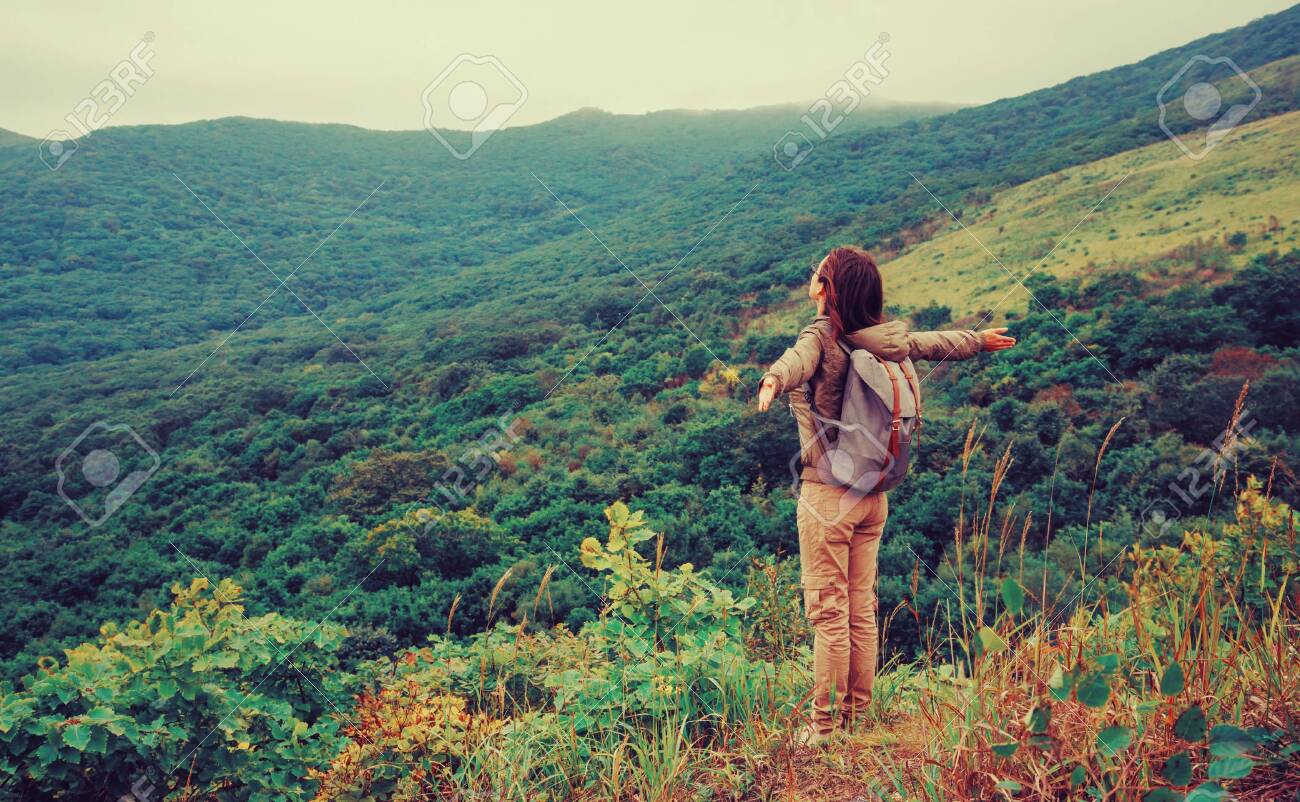 Freedom happy traveler woman standing with raised arms and enjoying a beautiful nature. - 128567296 Freedom happy traveler woman standing with raised arms and enjoying a beautiful nature. - 128567296
