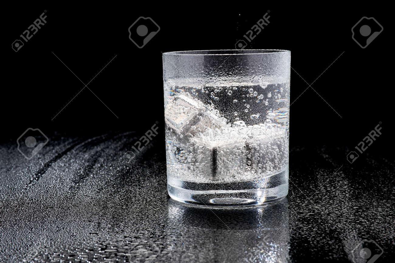 Glass of Soda or Coctail with steel cooling cubes on dark glass background - 169835482 Glass of Soda or Coctail with steel cooling cubes on dark glass background - 169835482