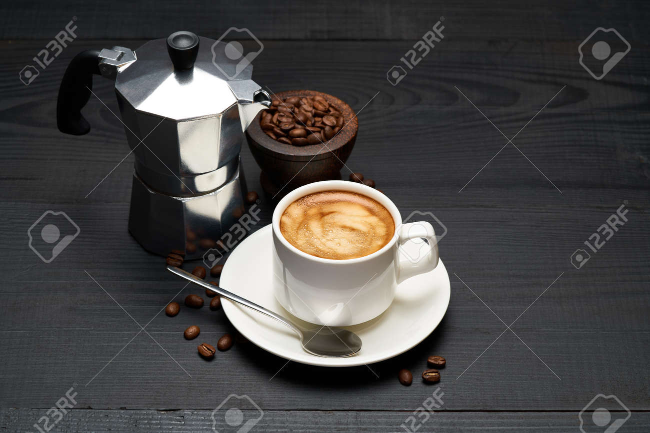 Cup of espresso coffee and mocha coffee maker on dark wooden background - 169835568 Cup of espresso coffee and mocha coffee maker on dark wooden background - 169835568