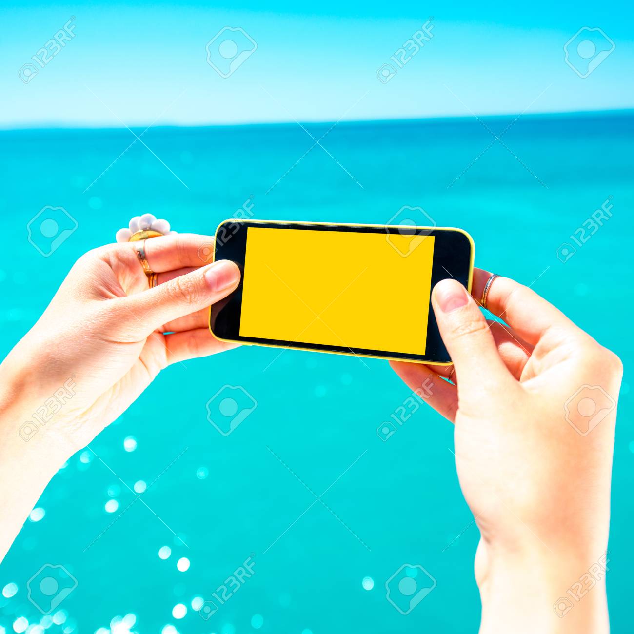 Tenant Un Telephone Jaune Avec Vide Ecran Sur La Mer Fond Bleu