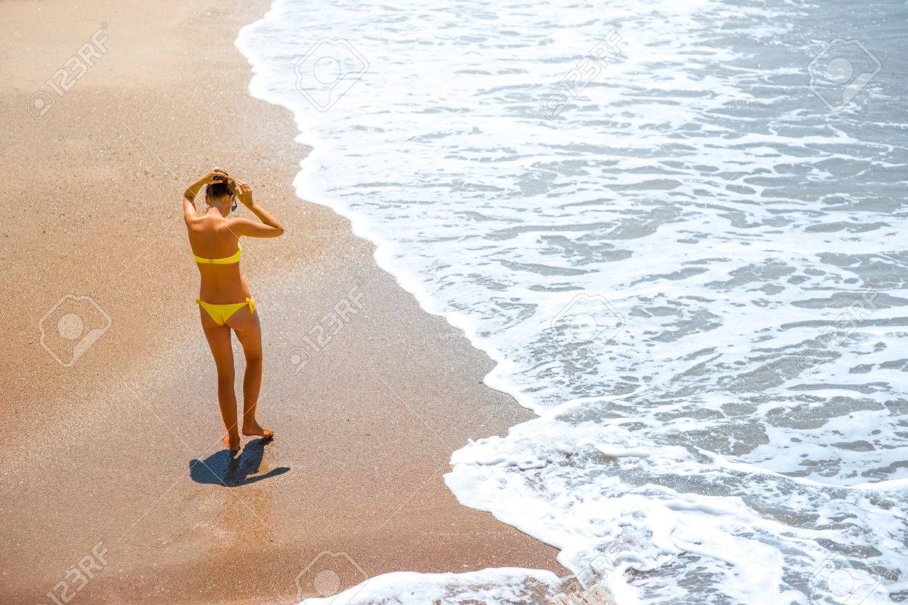 一般女性　水着 黄色の水着と白い泡の美しい海の海岸の上を歩く若い女性。テキスト領域の一般的な計画の上から背面図の写真素材・画像素材 Image 41460800
