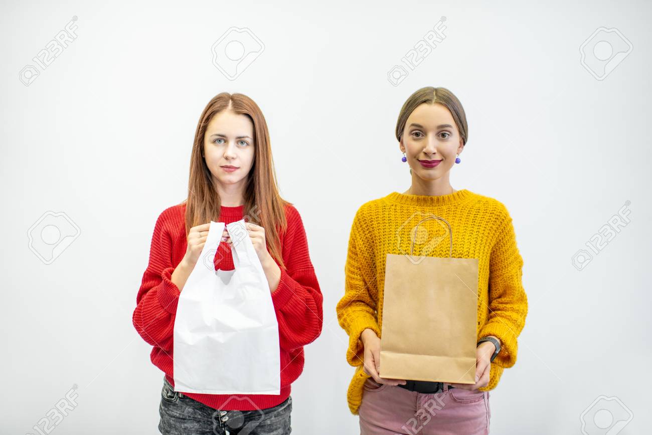 Portrait of a two women holding plastic and paper bags standing on the white background. Ecological in contrast to non recyclable packaging concept - 114781026 Portrait of a two women holding plastic and paper bags standing on the white background. Ecological in contrast to non recyclable packaging concept - 114781026