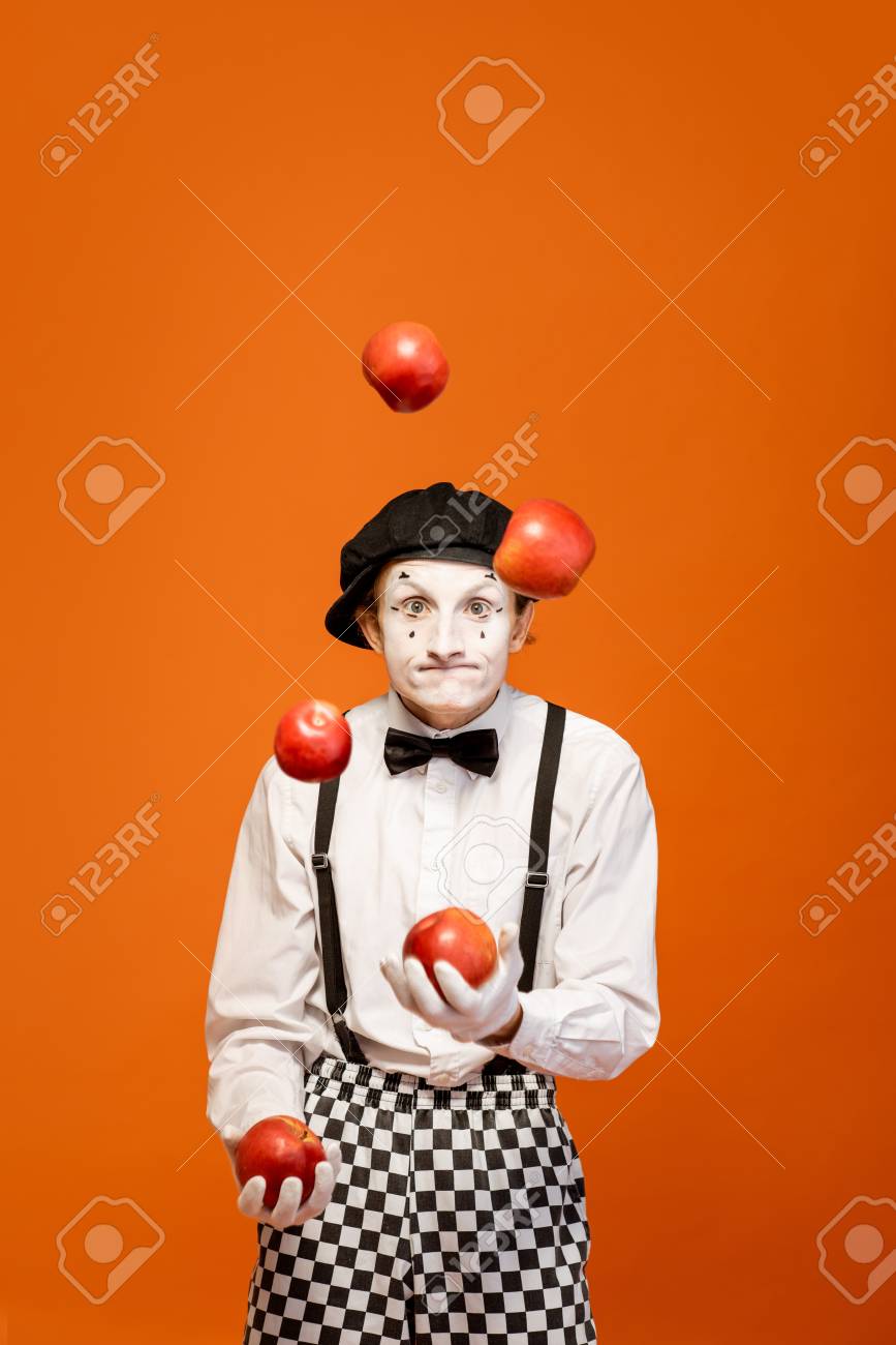 Portrait of an actor as a pantomime with white facial makeup showing expressive emotions on the orange background in the studio - 118134727 Portrait of an actor as a pantomime with white facial makeup showing expressive emotions on the orange background in the studio - 118134727
