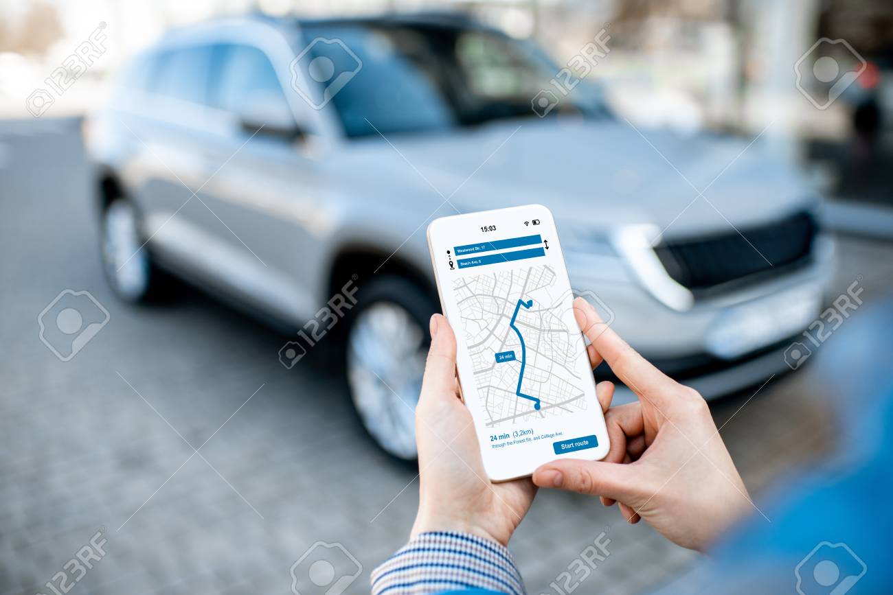 Woman using smart phone with navigation app, close-up view with modern car on the background - 119987400 Woman using smart phone with navigation app, close-up view with modern car on the background - 119987400
