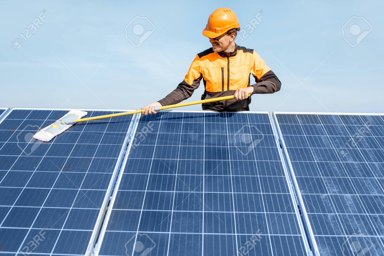 Professional cleaner in protective workwear cleaning solar panels with a mob. Concept of solar power plant cleaning service - 133698292 Professional cleaner in protective workwear cleaning solar panels with a mob. Concept of solar power plant cleaning service - 133698292