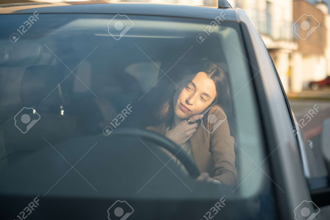 Young woman talking on the phone and driving a car - 167030284 Young woman talking on the phone and driving a car - 167030284
