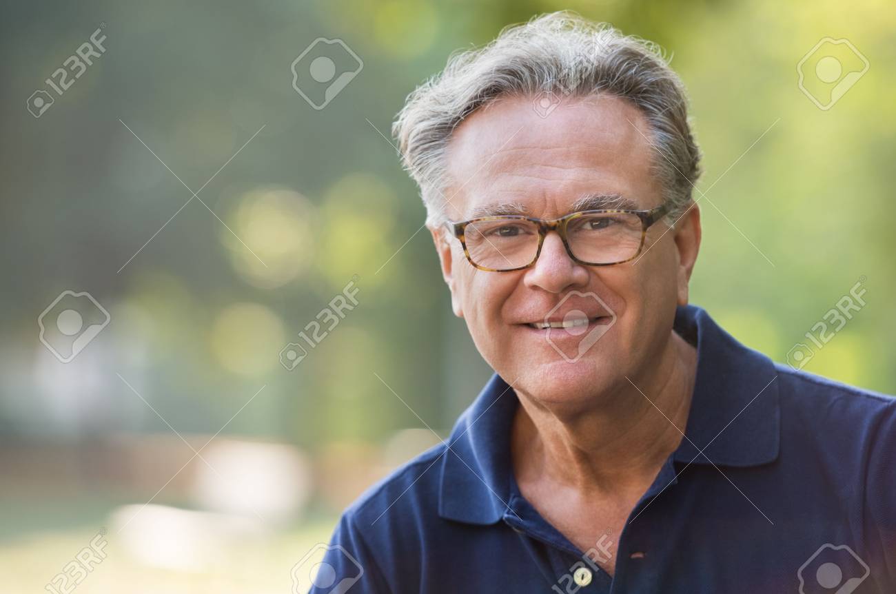 Portrait of senior man smiling and loooking at camera. Face of a happy old man wearing eyeglasses outdoor. Retired man with grey hair relaxing at park during morning. - 64821190 Portrait of senior man smiling and loooking at camera. Face of a happy old man wearing eyeglasses outdoor. Retired man with grey hair relaxing at park during morning. - 64821190