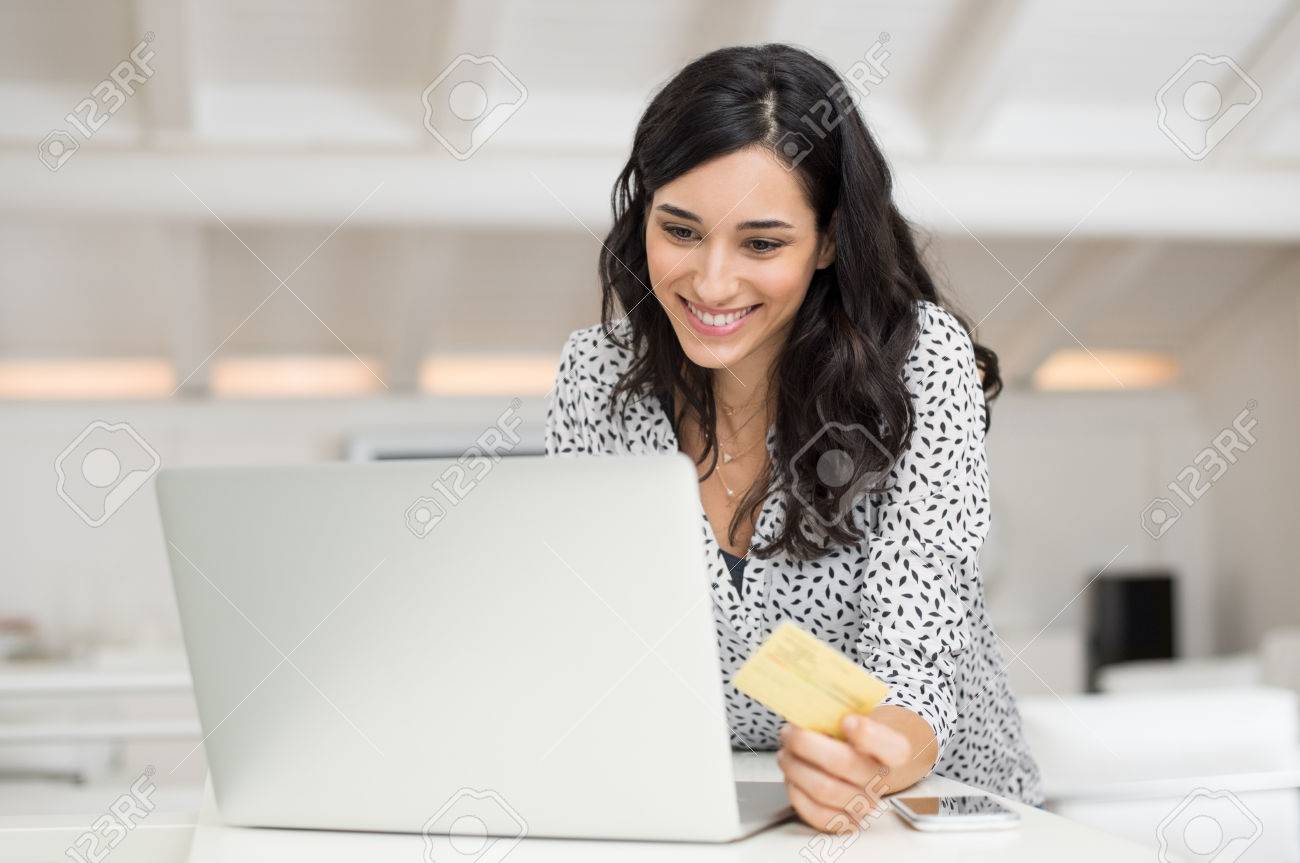 happy young woman holding a credit card and shopping online at