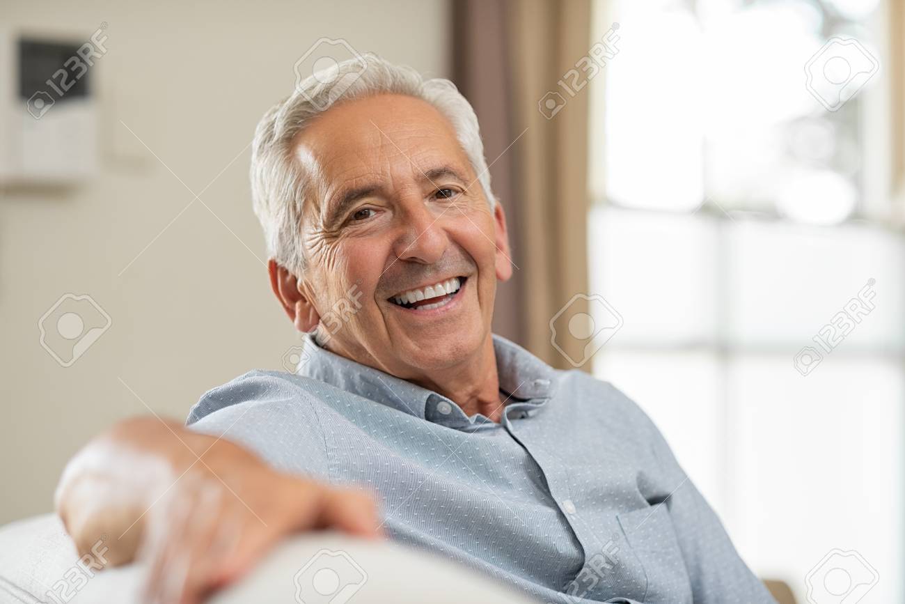 Portrait Of Happy Senior Man Smiling At Home. Old Man Relaxing On Sofa And  Looking At Camera. Portrait Of Elderly Man Enjoying Retirement. Stock  Photo, Picture and Royalty Free Image. Image 107596045.