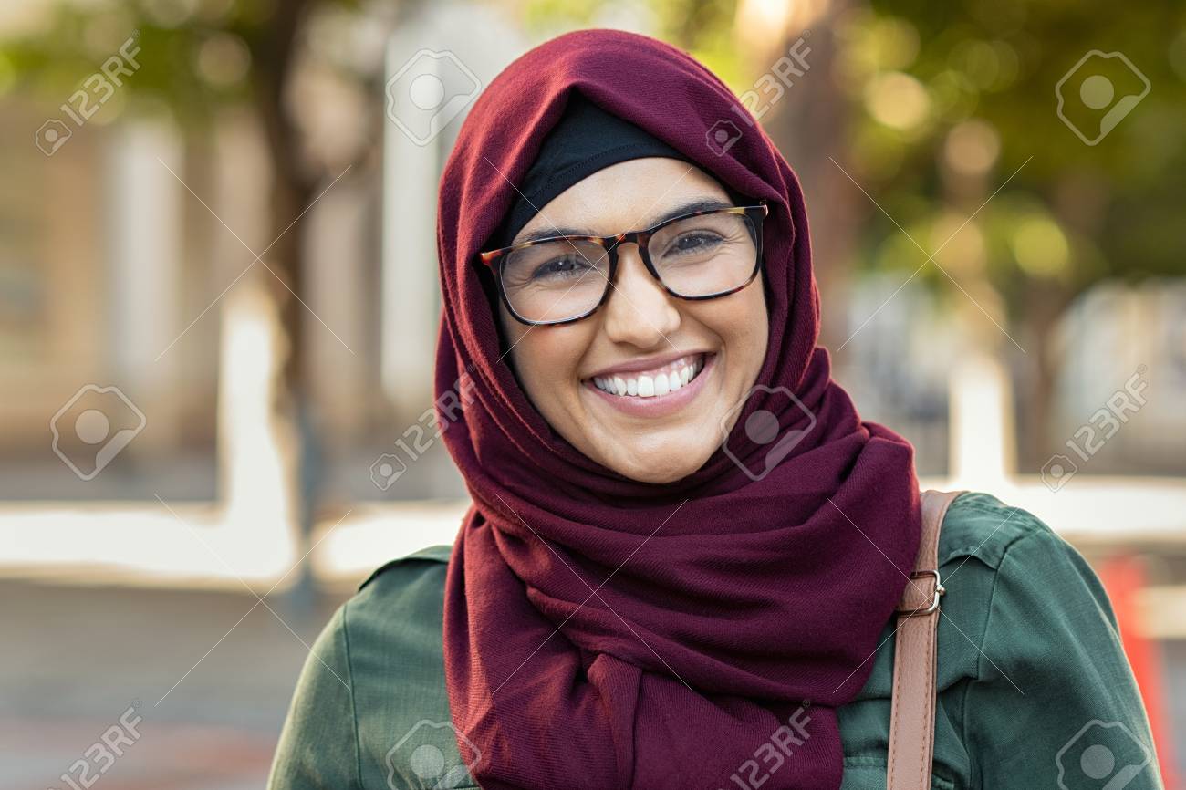 Beautiful Young Muslim Woman Wearing Hijab And Spectacles. Islamic Curvy Woman Looking At Camera. Closeup Face Of Arabic Girl Wearing Eyeglasses And Looking At Camera With A Big Grin. Stock Photo, Picture