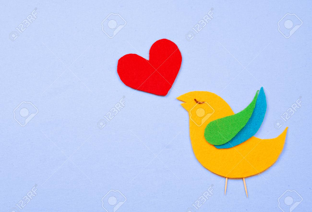 Un Oiseau Fantaisie En Forme De Feutre Jaune Vert Et Bleu Avec Un Cur De Feutre Rouge Qui Représente La Chanson De Loiseau Tous Sont Sur Un Fond