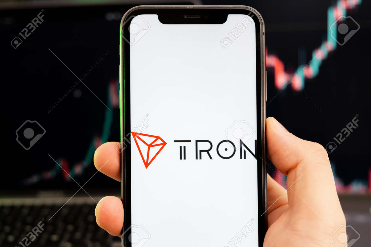 녹색 배경 차트의 증가 추세와 함께 사람 손에 있는 스마트폰 화면의 Tron Trx 암호화폐 로고 로열티 무료 사진, 그림, 이미지  그리고 스톡포토그래피. Image 183375059
