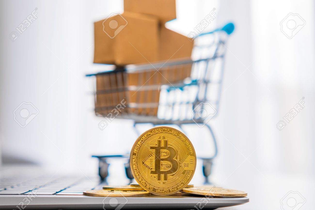背景に段ボール箱を持つミニおもちゃのショッピングカートの横にコインビットコイン。国際ネットワーク決済のコンセプト。の写真素材・画像素材 Image  204451709