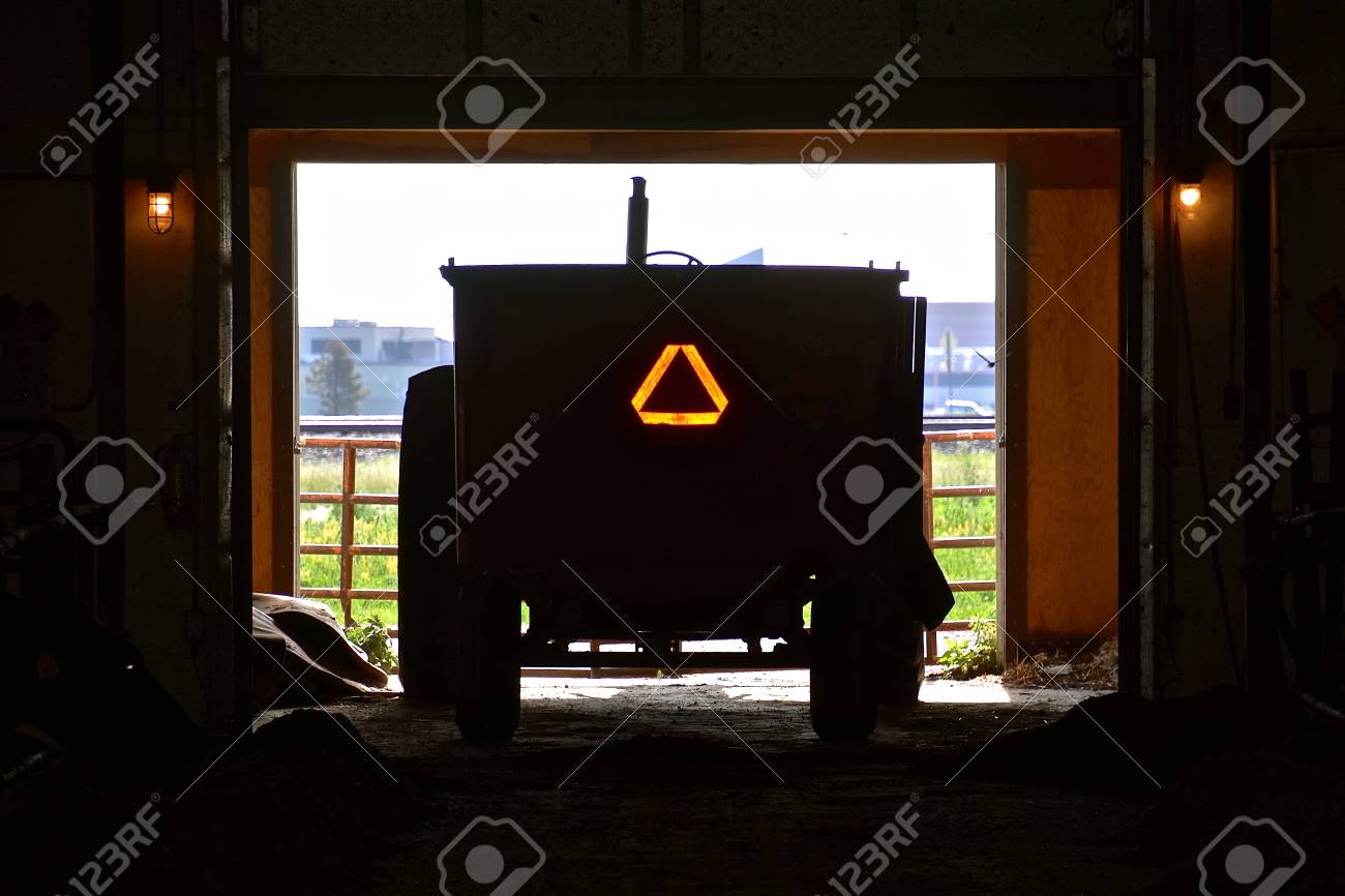 A feed cart backed into a shed displays the Slow Moving Vehicle sign. - 105950732 A feed cart backed into a shed displays the Slow Moving Vehicle sign. - 105950732