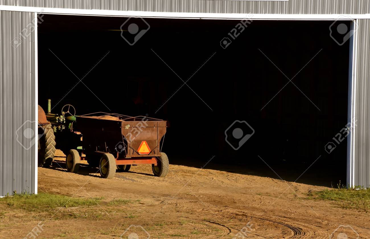 A grain wagon loaded with shelled corn displaying a SMV vehicle sign is parked in a huge metal quonset building. - 115503445 A grain wagon loaded with shelled corn displaying a SMV vehicle sign is parked in a huge metal quonset building. - 115503445