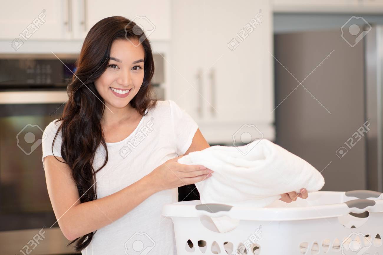 Woman folding the laundry in her home - 112358290 Woman folding the laundry in her home - 112358290