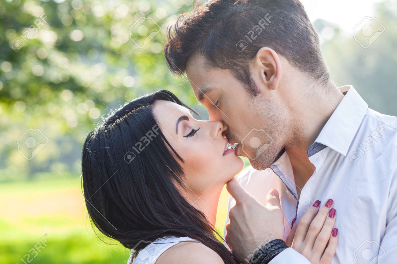 バック グラウンドで太陽光で公園でロマンチックなキス の写真素材 画像素材 Image