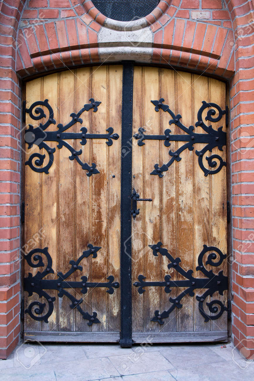 An Old Antique Wooden Door With Wrought Iron Ornate Reinforcement An old antique wooden door with wrought iron ornate reinforcement in Budapest, Hungary. Stock - An Old Antique Wooden Door With Wrought Iron Ornate Reinforcement