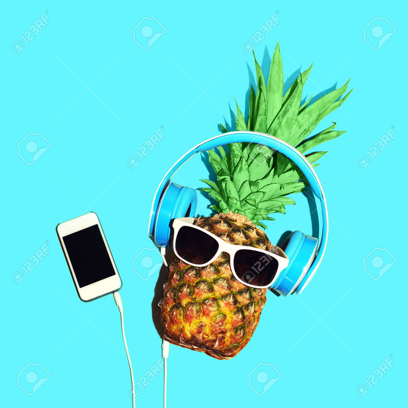 ファッション パイナップル サングラスとヘッドフォンは 青色の背景にスマート フォンで音楽を聴いてください の写真素材 画像素材 Image