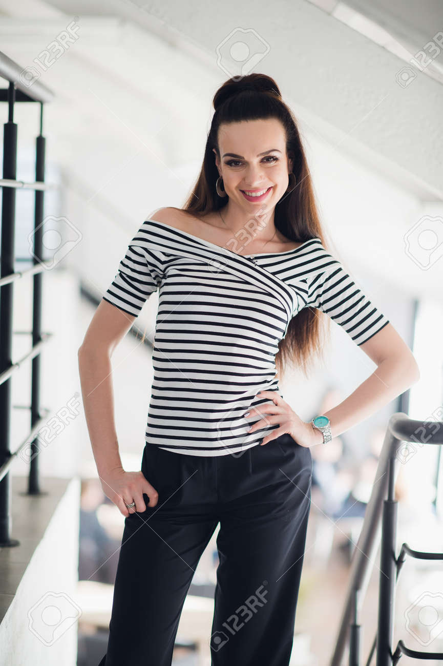 モダンなカフェで立っている笑顔の若い女性のファッションの肖像画 美しい大人ブルネット女性彼女の仕事からリラックス の写真素材 画像素材 Image