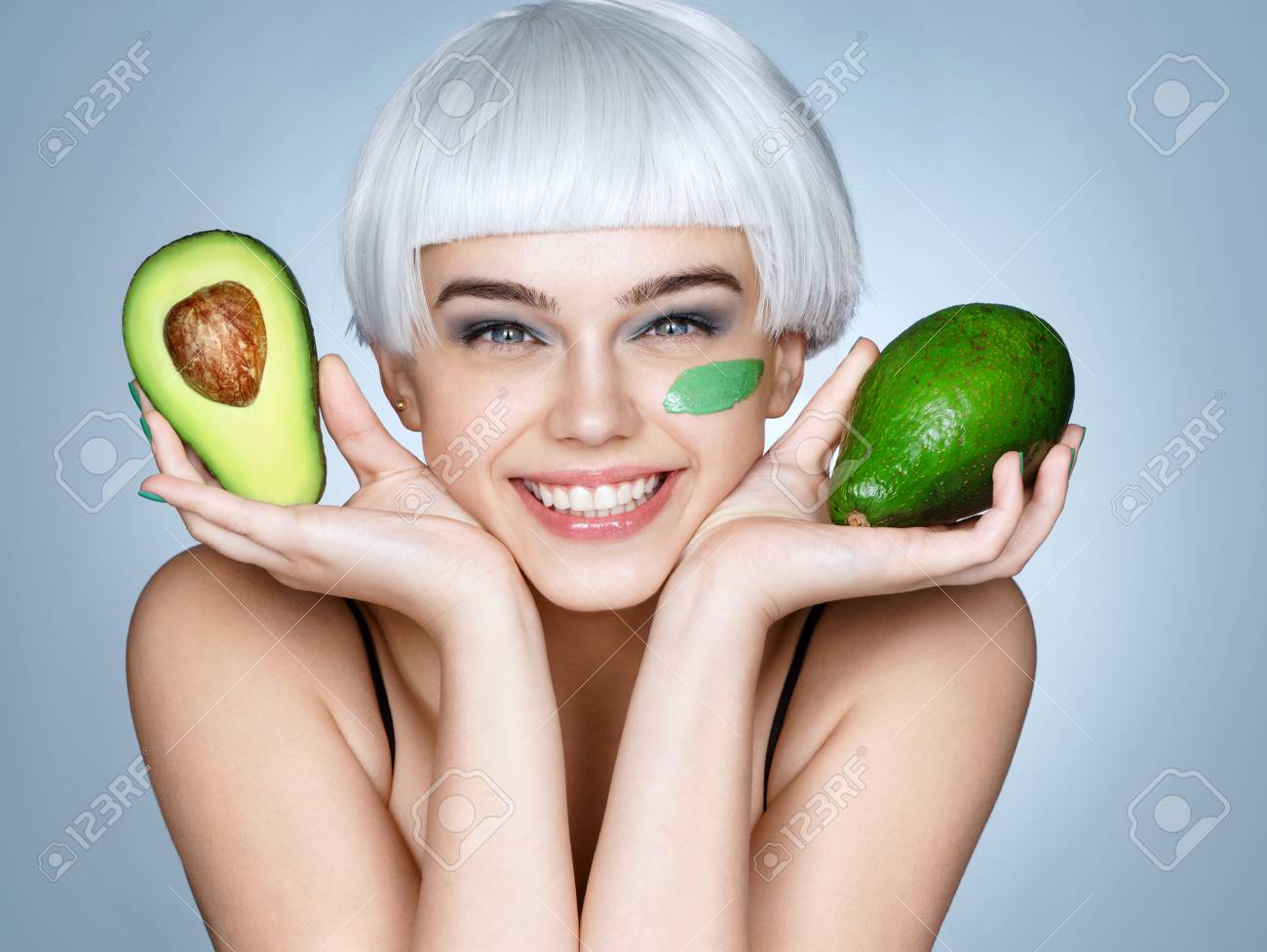 Happy smiling girl with green avocado. Photo of smiling blonde girl on blue background. Skin care and beauty concept. - 88679197 Happy smiling girl with green avocado. Photo of smiling blonde girl on blue background. Skin care and beauty concept. - 88679197