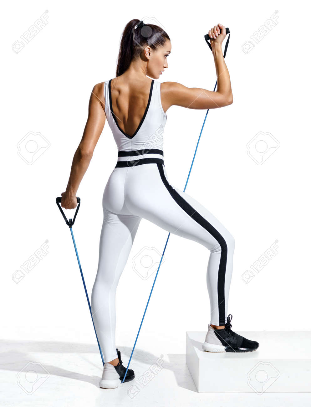 Fitness girl performs exercising with resistance band. Photo of sporty girl in fashionable sportswear isolated on white background. Strength and motivation. Full length - 103368276 Fitness girl performs exercising with resistance band. Photo of sporty girl in fashionable sportswear isolated on white background. Strength and motivation. Full length - 103368276