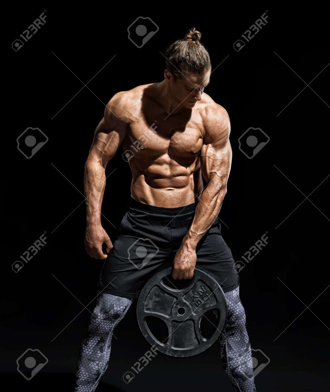 Sportive young man resting after workout with heavy weight disks. Photo of athletic man with torso and good physique on black background. Strength and motivation - 107009880 Sportive young man resting after workout with heavy weight disks. Photo of athletic man with torso and good physique on black background. Strength and motivation - 107009880