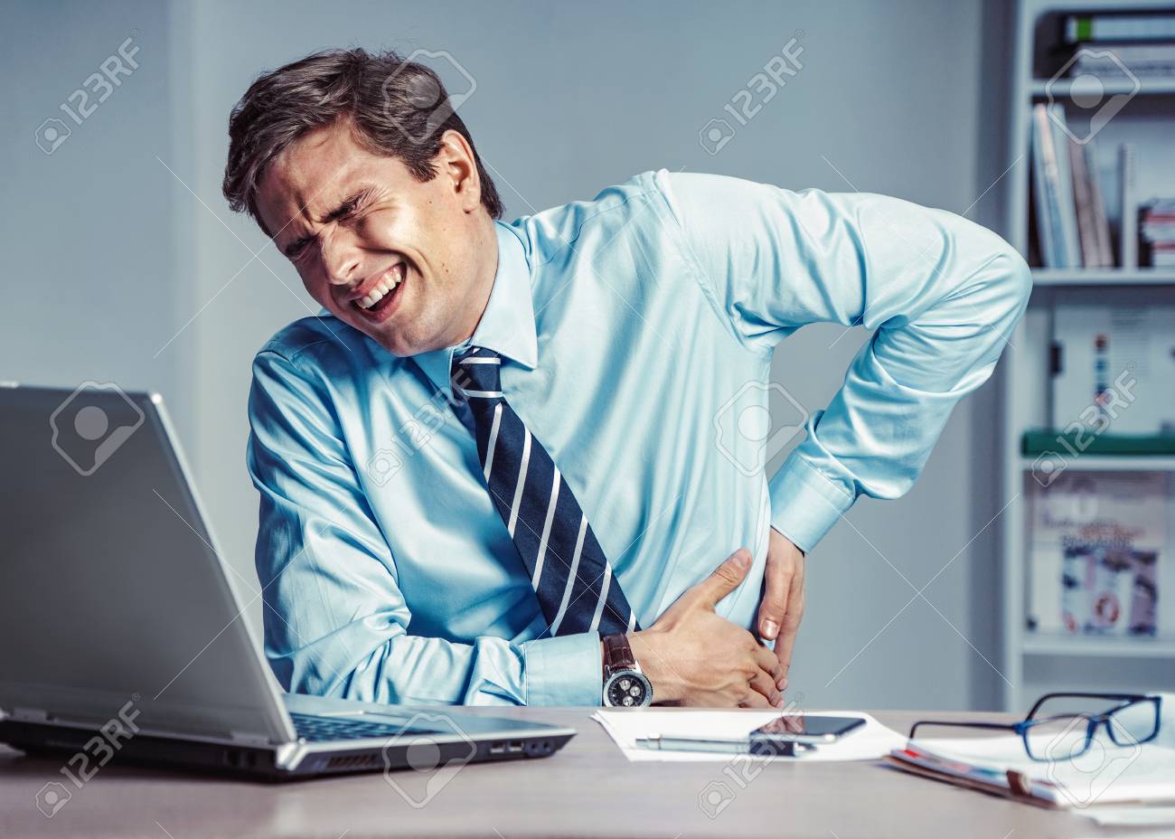 Employee suffers from severe pain in back. Photo of man working in the office. Medical concept. - 113557024 Employee suffers from severe pain in back. Photo of man working in the office. Medical concept. - 113557024