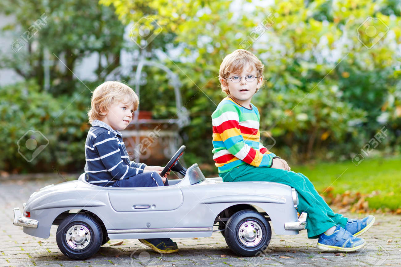 夏の庭園 屋外の大きな古いおもちゃの車で遊ぶ 2 つの幸せな子供たち双子の男の子と暖かい日に友人 の写真素材 画像素材 Image