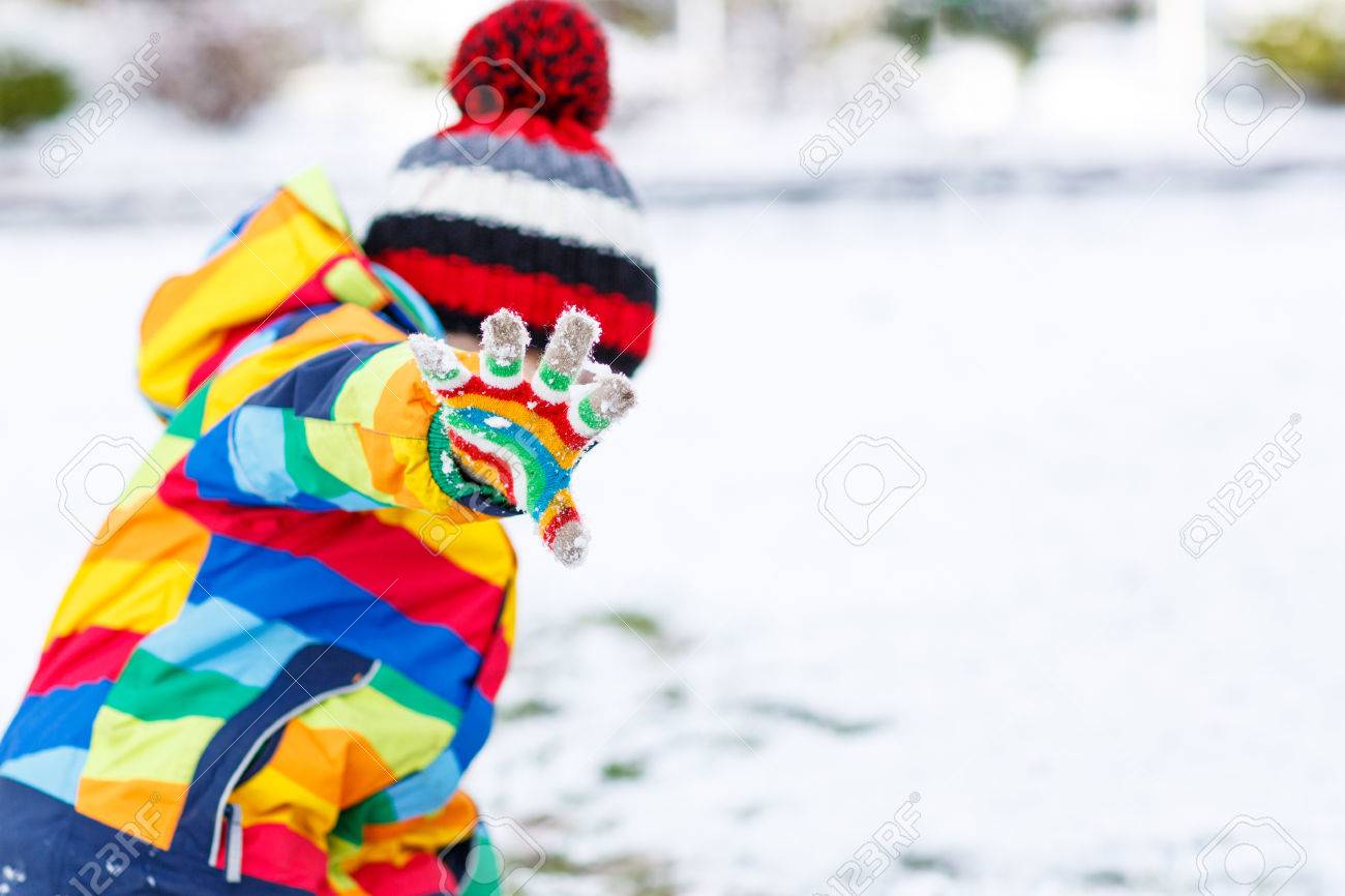 Cute Little Funny Boy In Colorful Winter Clothes Playing Fighting With Snow Ball Outdoors On Cute Little Funny Boy In Colorful Winter Clothes Playing Fighting With Snow Ball Outdoors On