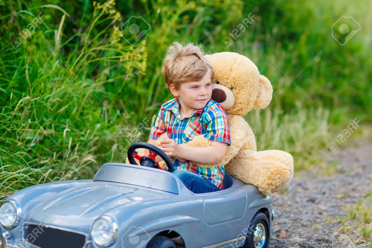 小さな幼児子供男の子大きなおもちゃの車を運転し ぬいぐるみの熊 屋外と遊んで楽しい時を過します 自然の風景の中の暖かい夏の日を楽しむ子供 の写真素材 画像素材 Image