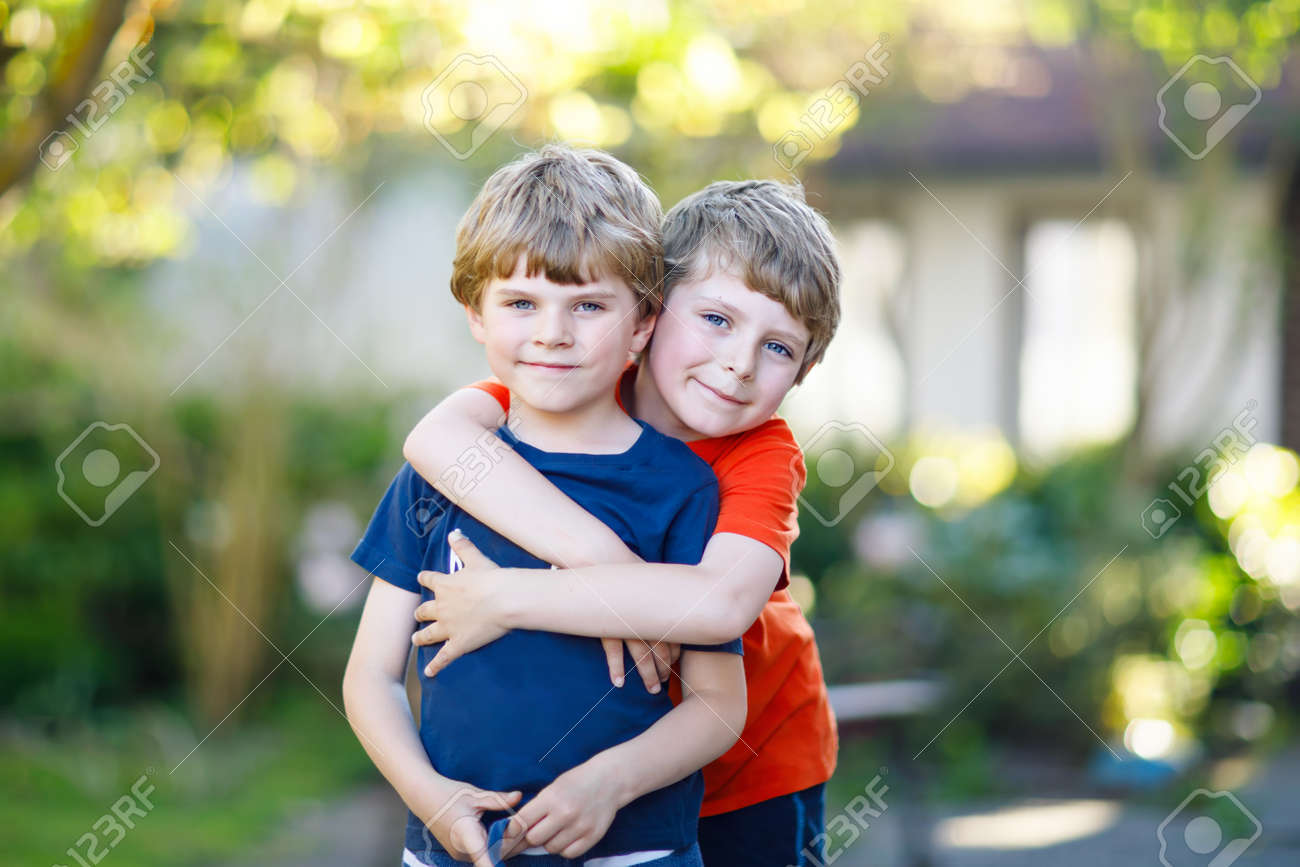 two little active school kids boys twins and siblings hugging