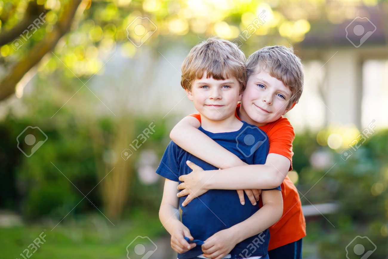 two little active school kids boys twins and siblings hugging