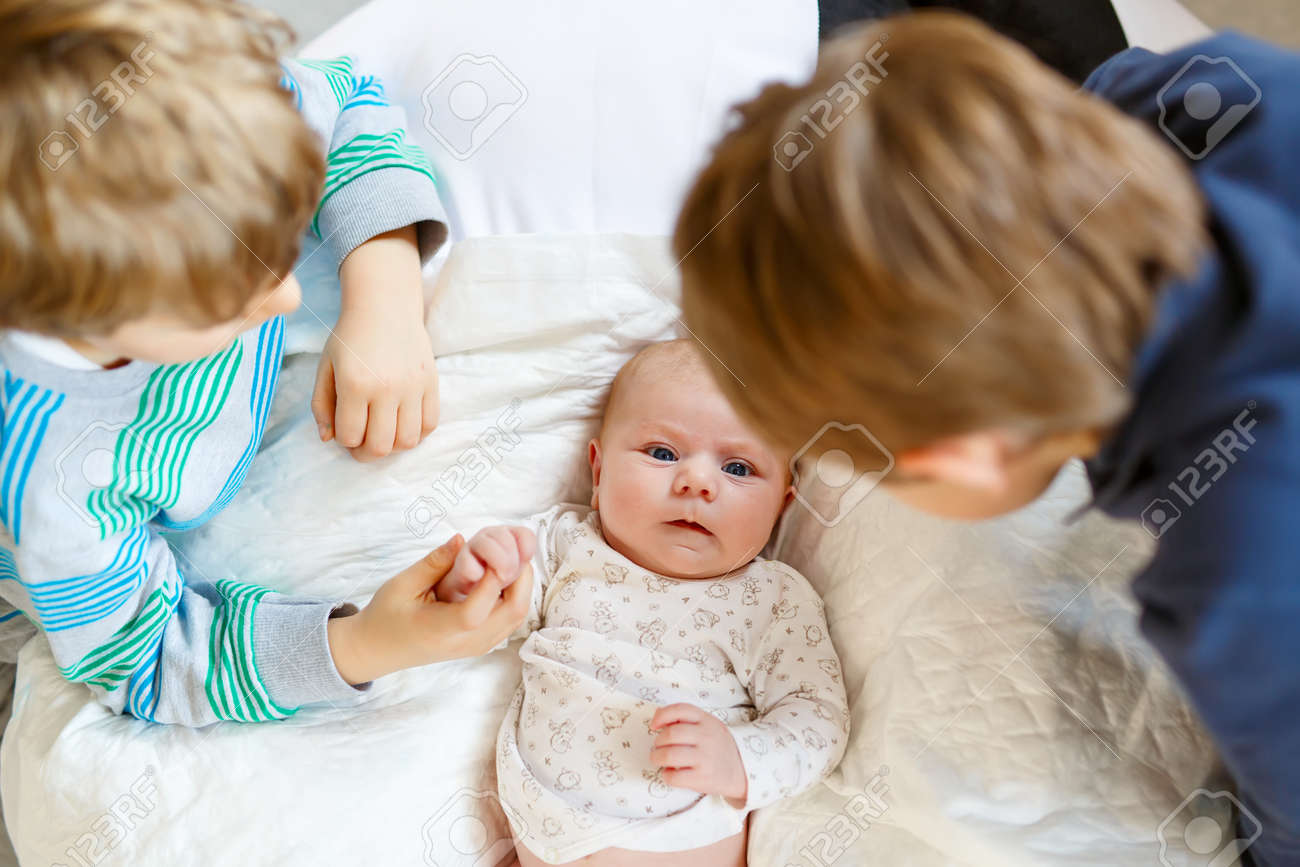 Two little kids boys with newborn baby girl, cute sister. Siblings. Brothers and baby playing with colorful toys and rattles together. Kids bonding. Family of three bonding, love - 121029530 Two little kids boys with newborn baby girl, cute sister. Siblings. Brothers and baby playing with colorful toys and rattles together. Kids bonding. Family of three bonding, love - 121029530